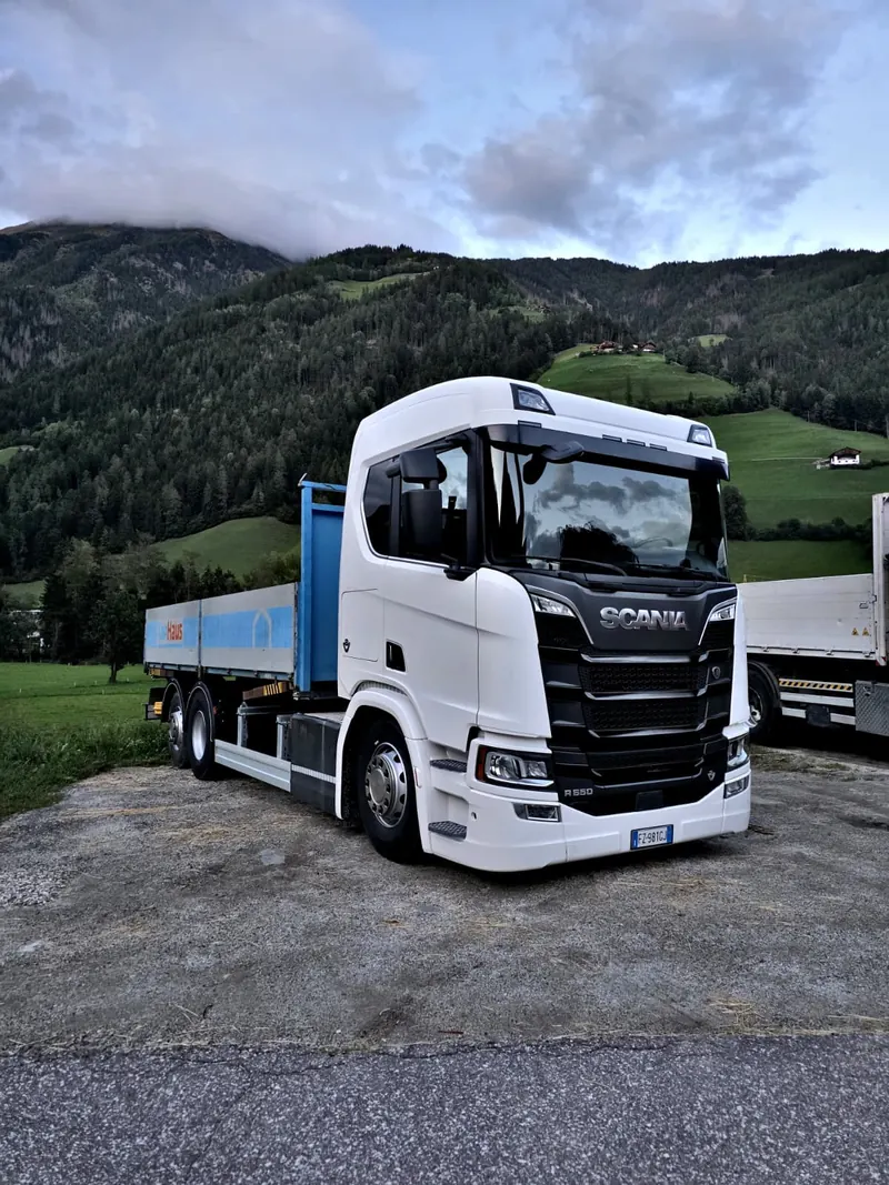 Weißer Scania R 650 vor bewaldeten Berghängen