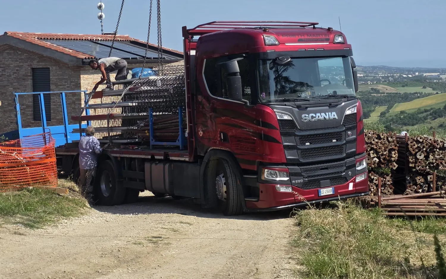 Roter Scania von Transporte Prieth Martin beim Abladen von Baustahl mit dem Kran auf einer Baustelle