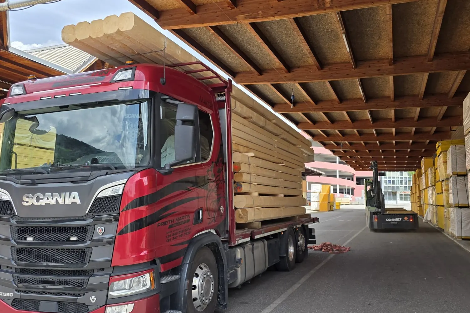 Lkw mit Bauholz beladen unter dem Vordach eines Holzlagers